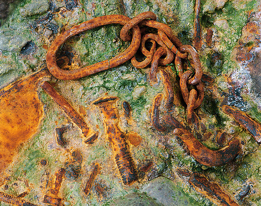 Rusty chain on sand and stone