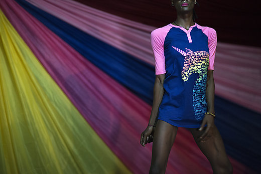 Transgender man standing in front of draped material, wearing t-shirt with an image of a unicorn.
